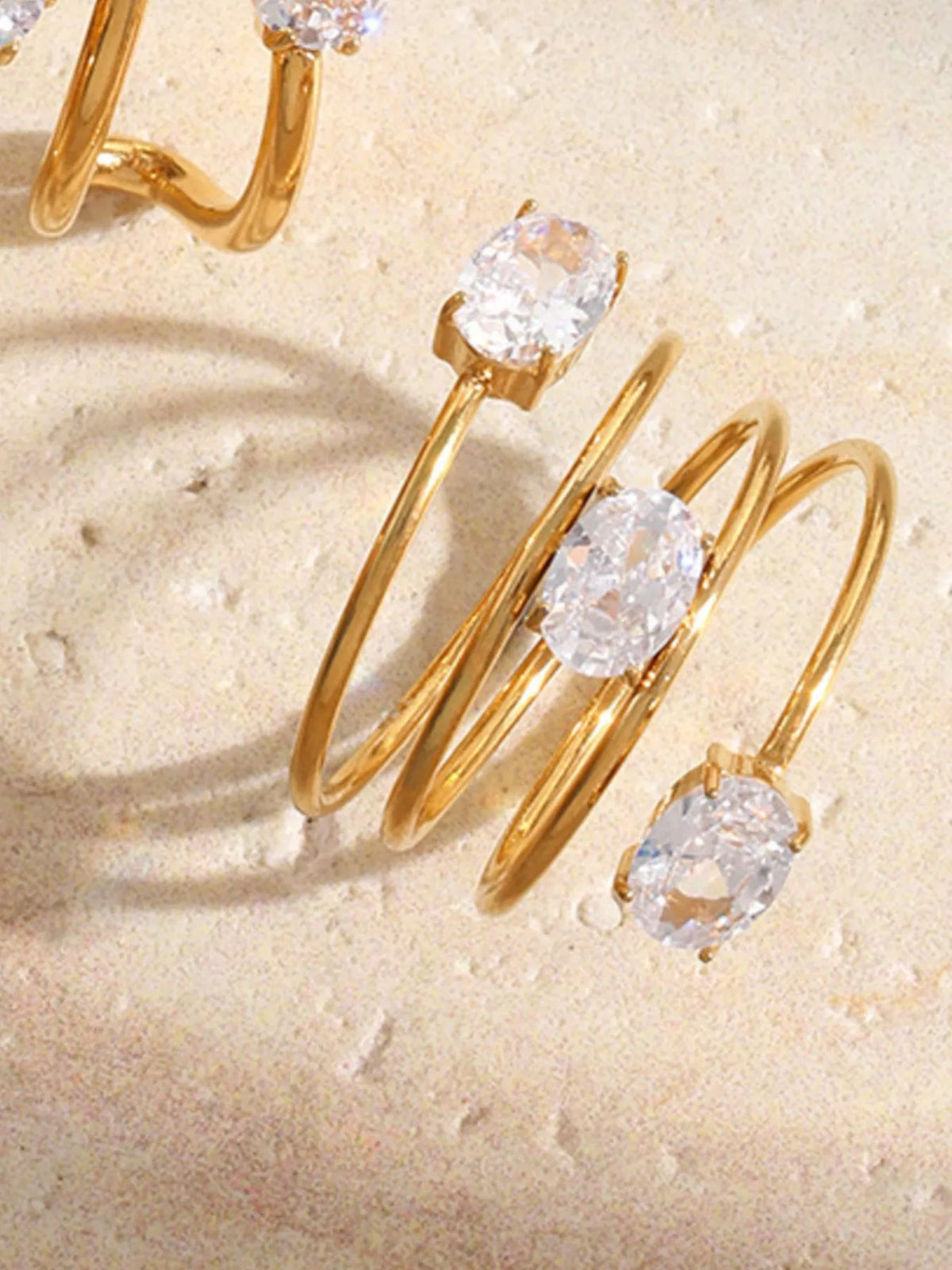 Stacked gold-tone open ring with clear oval stones worn on hand