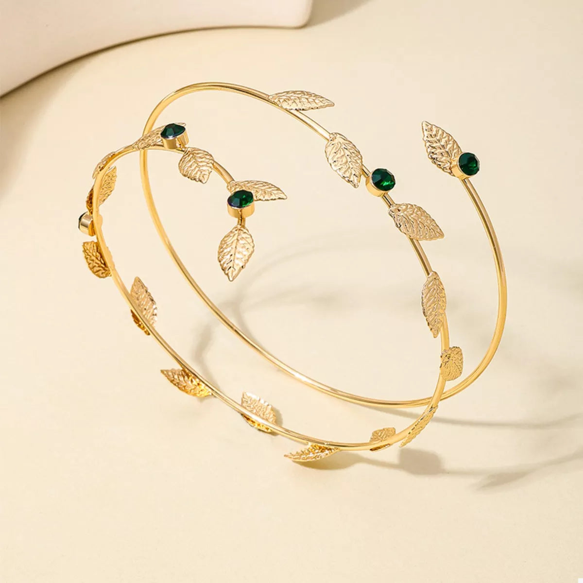Gold-tone leaf bracelet with green accents displayed from above