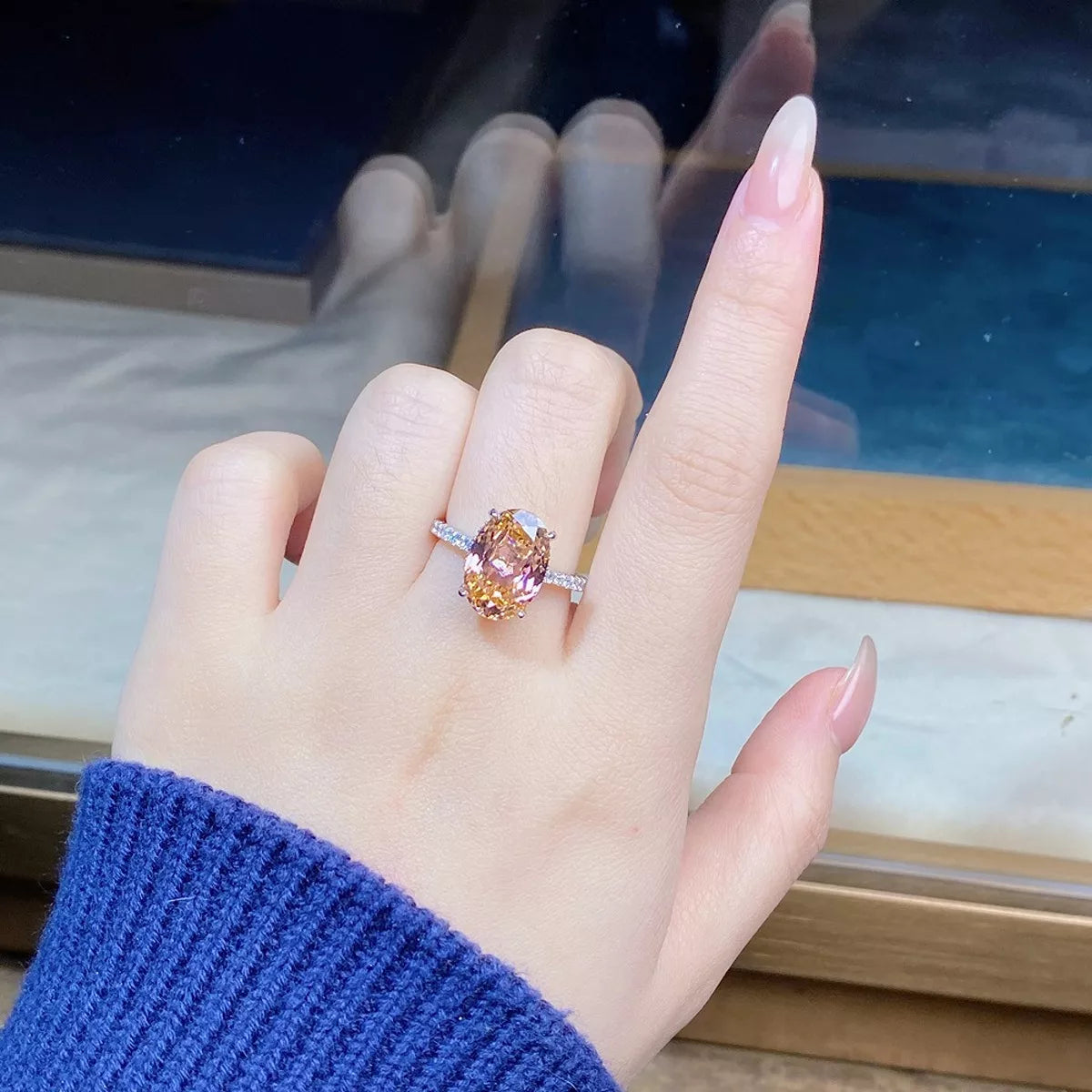 Oval pink gemstone ring with clear accents shown on a hand