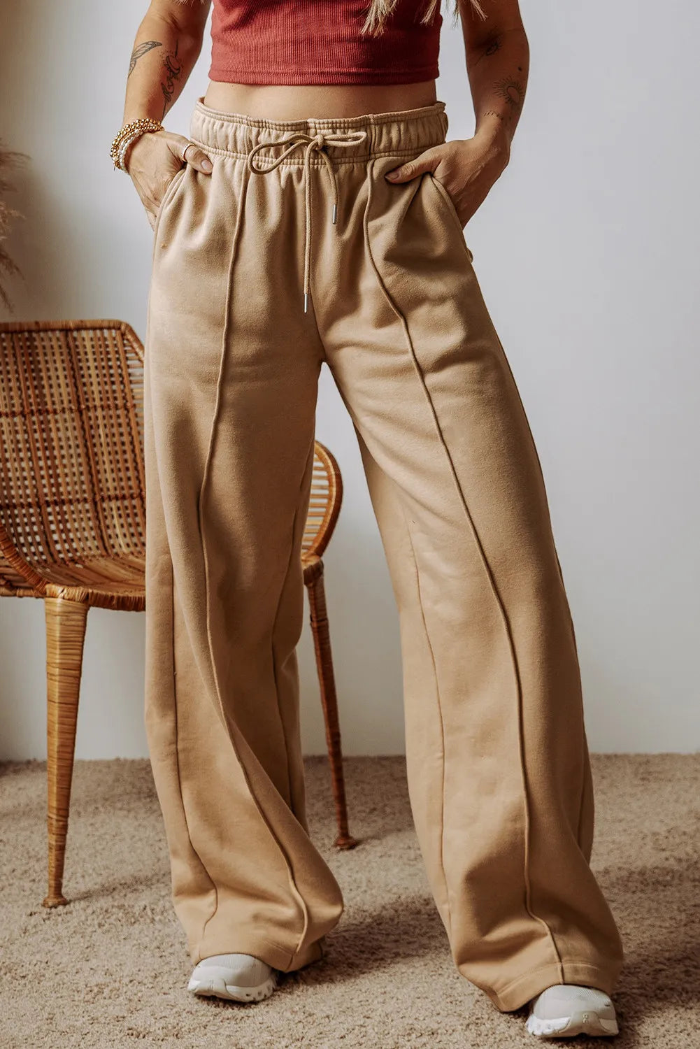 Model wearing tan drawstring trousers with roomy wide legs and front pockets.
