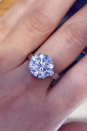 Round moissanite solitaire worn on a finger, showing the bright center stone.