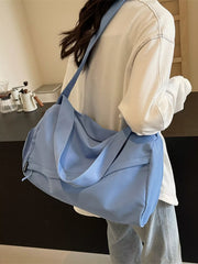 Blue travel duffel bag carried over the shoulder with short handles draped across the front