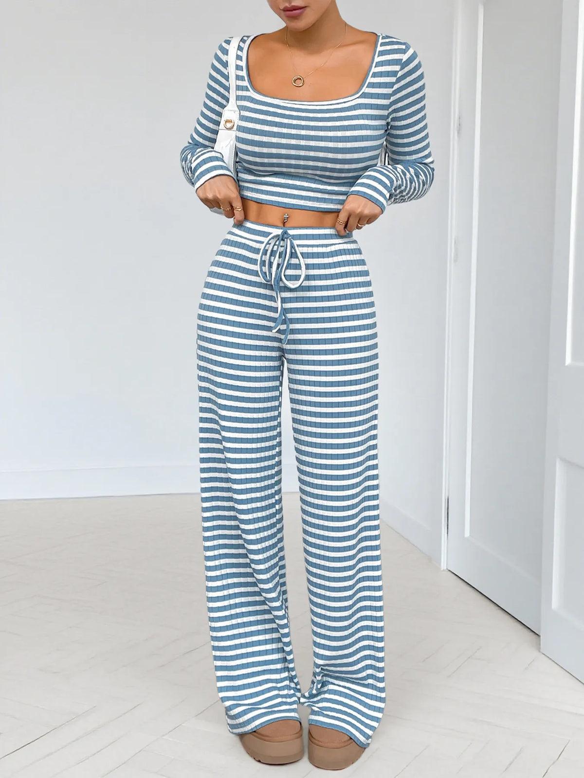 Model seated in blue-and-white striped long-sleeve crop top and pants