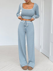 Model seated in blue-and-white striped long-sleeve crop top and pants