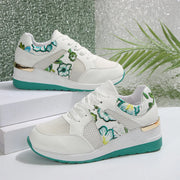 Pair of white sneakers with green floral panels and turquoise wedge soles