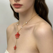 Gold-tone flower pendant necklace with pearl accents worn on a model