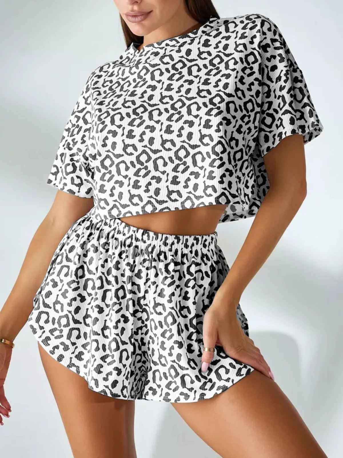 Model wearing the matching leopard-print crop top and high-waisted shorts, angled pose.