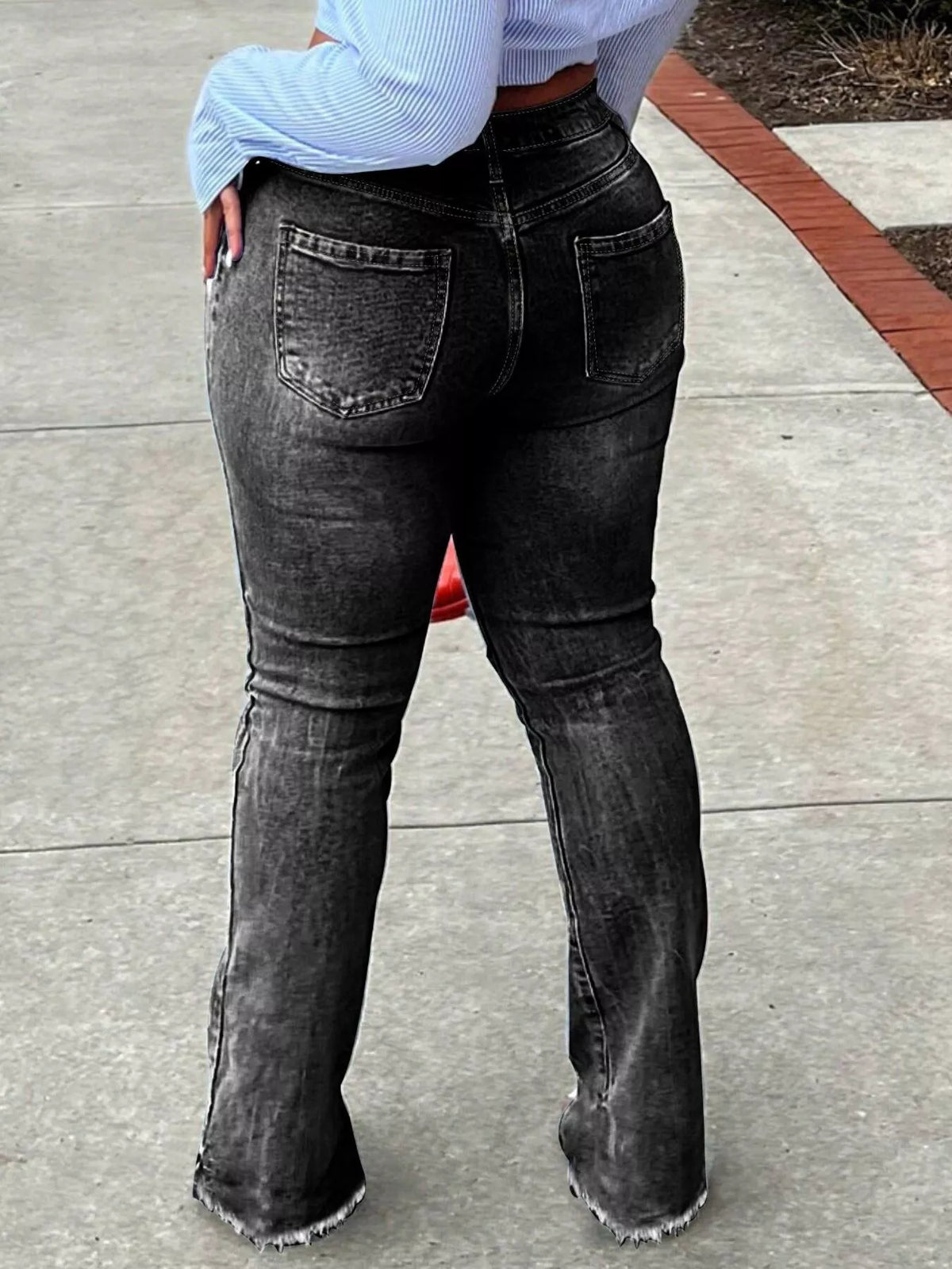 Close view of flare jeans showing distressed knee openings and a raw split hem.