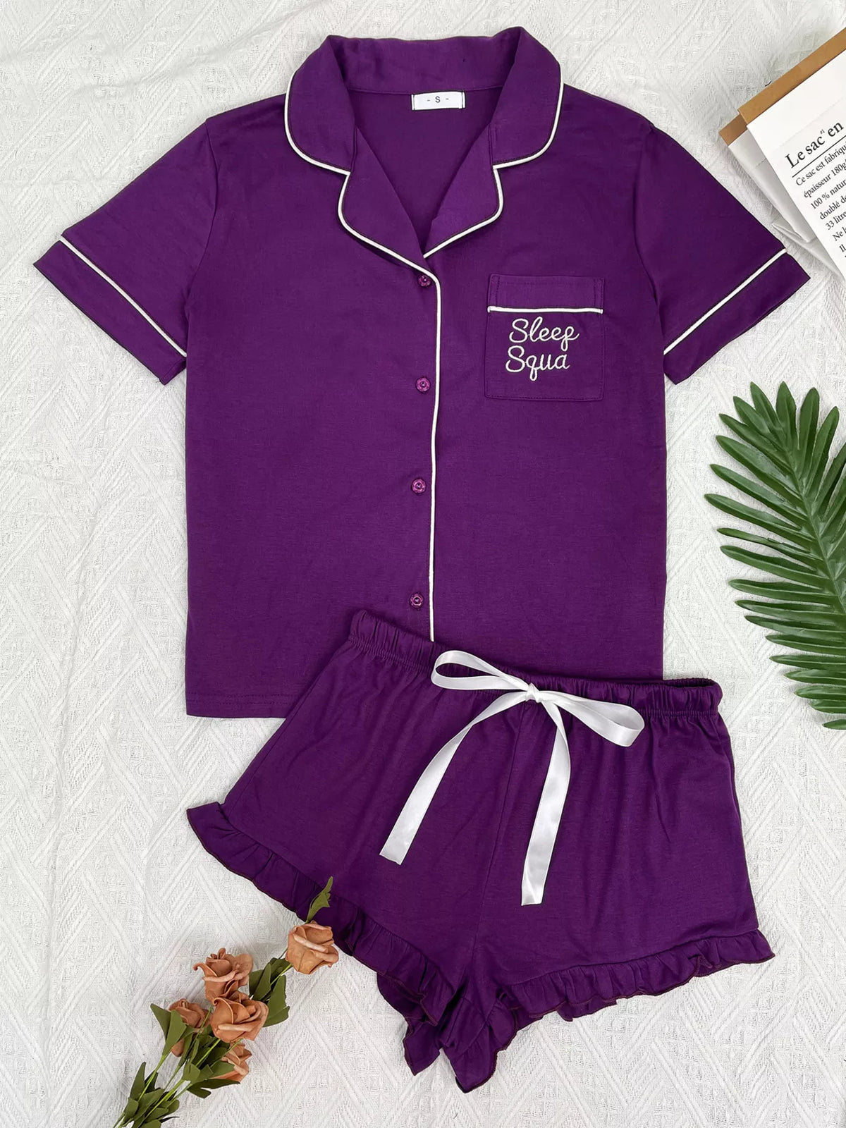 Purple button-down pajama set with white piping and matching ruffle shorts, front view