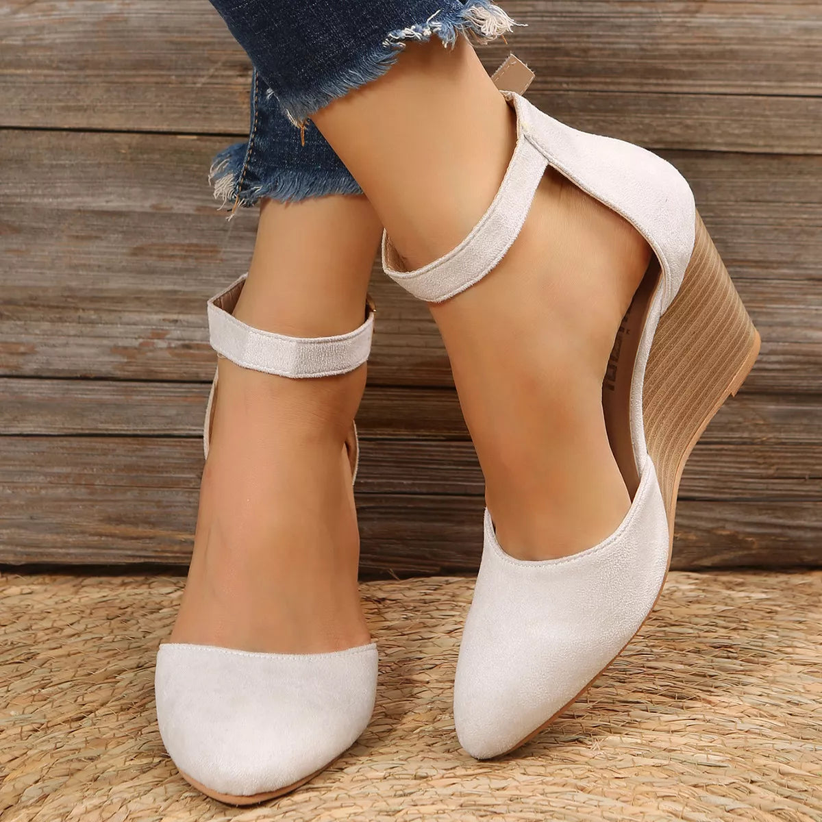 White pointed-toe wedge sandals worn with ankle straps