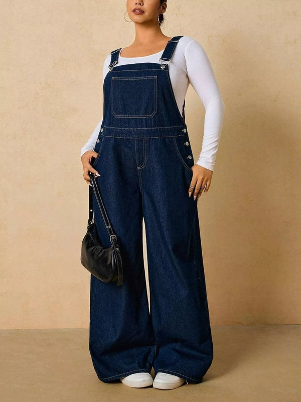 Dark blue denim overalls shown at an angle while holding a small black bag.