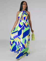 Blue and lime geometric maxi dress on a model holding the pleated skirt beside a green handbag.
