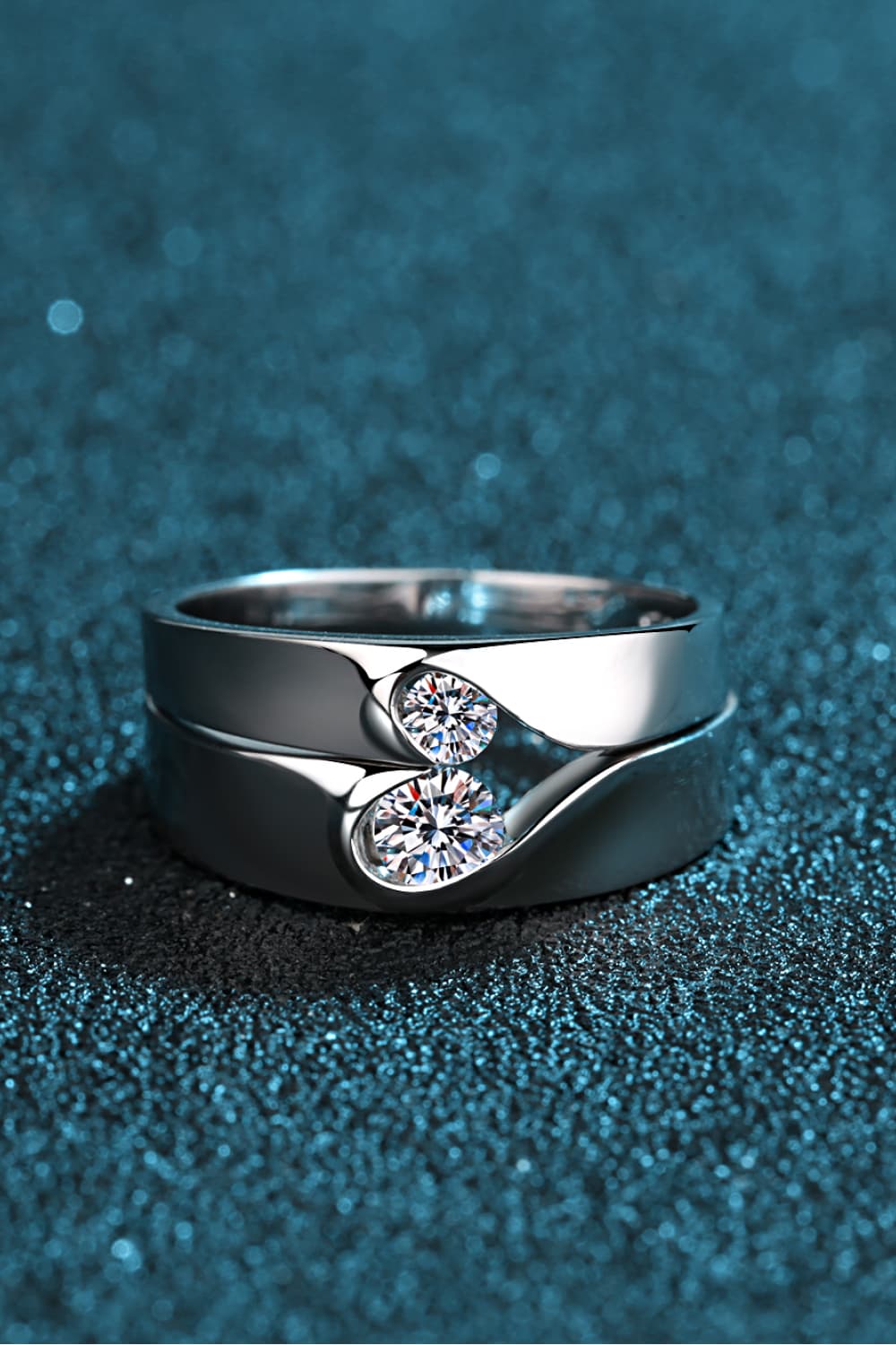 Close view of a silver crossover ring set with two round moissanite stones.