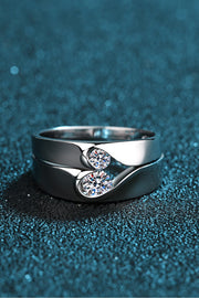 Close view of a silver crossover ring set with two round moissanite stones.