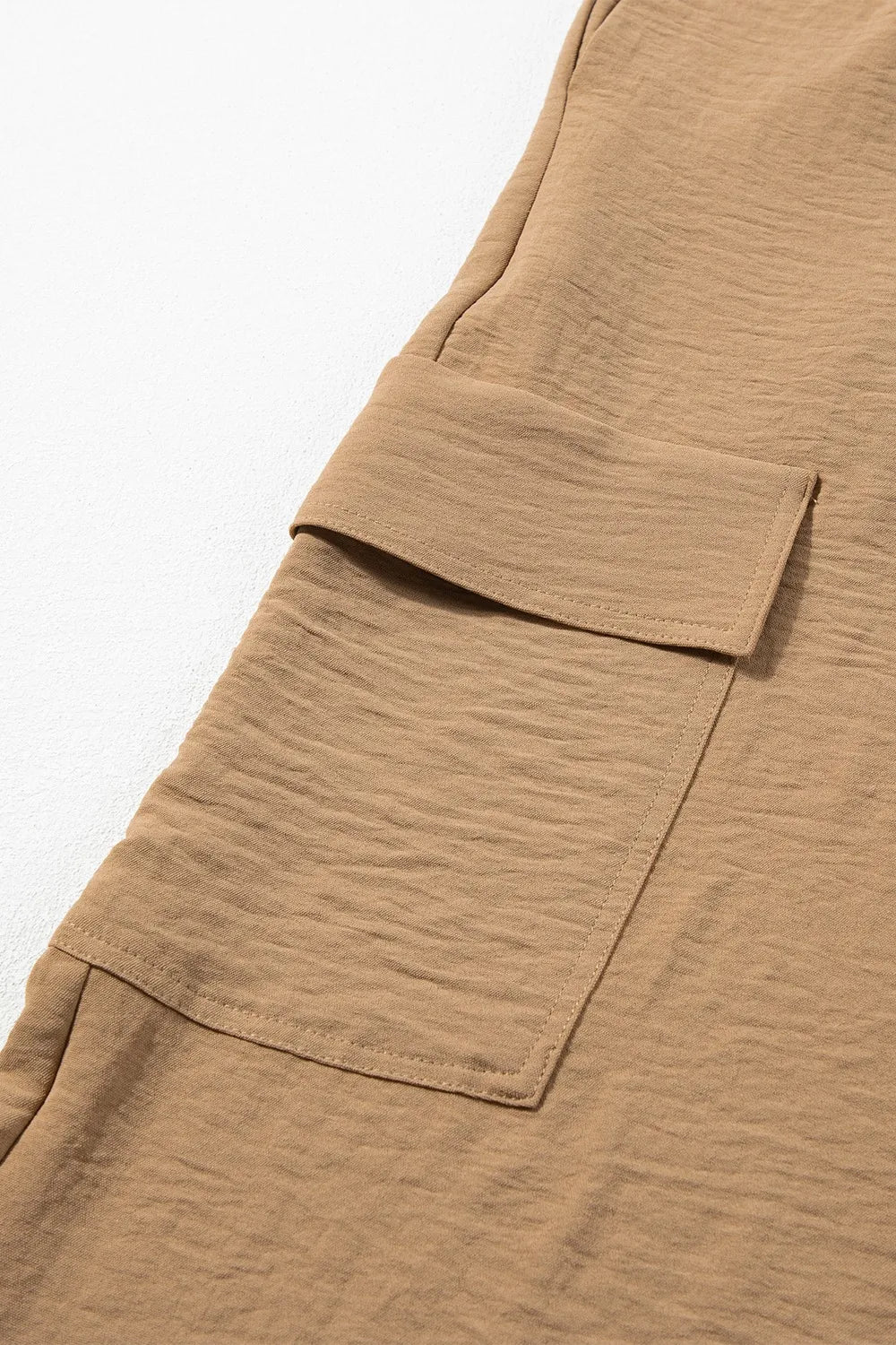 Close-up of the flap cargo pocket on tan utility trousers
