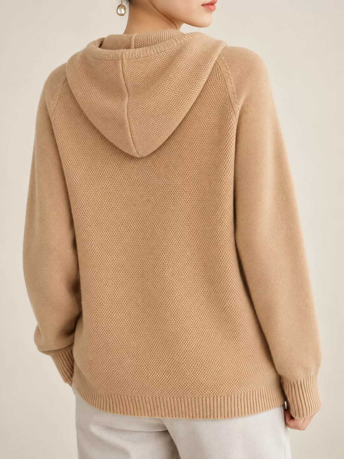 Back view of the light tan knit sweater showing its hood and ribbed hem.