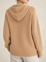 Back view of the light tan knit sweater showing its hood and ribbed hem.