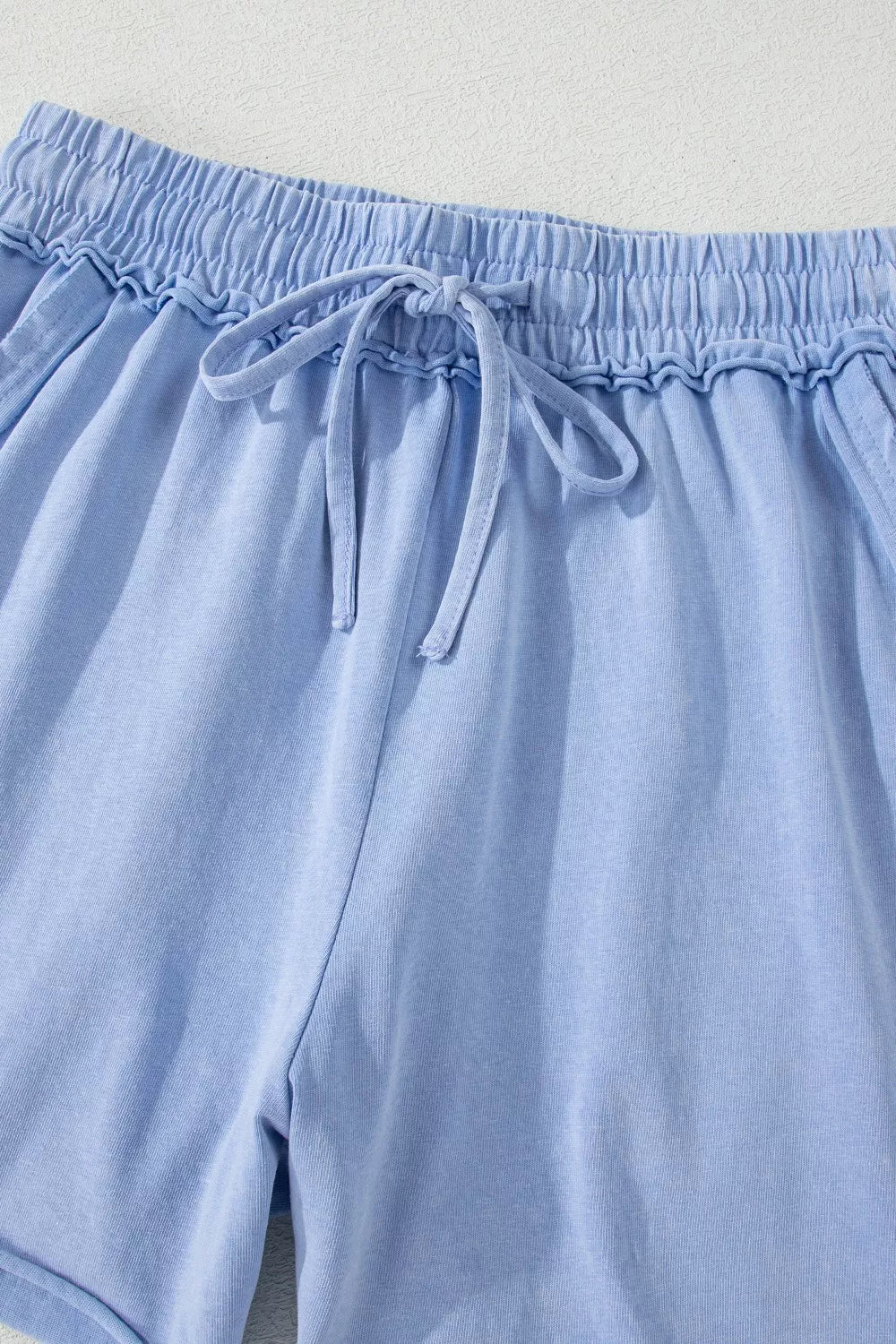 Close-up of gathered elastic waistband and drawstring on blue shorts