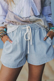 Front view of light blue striped shorts and white waist drawstring on a model.