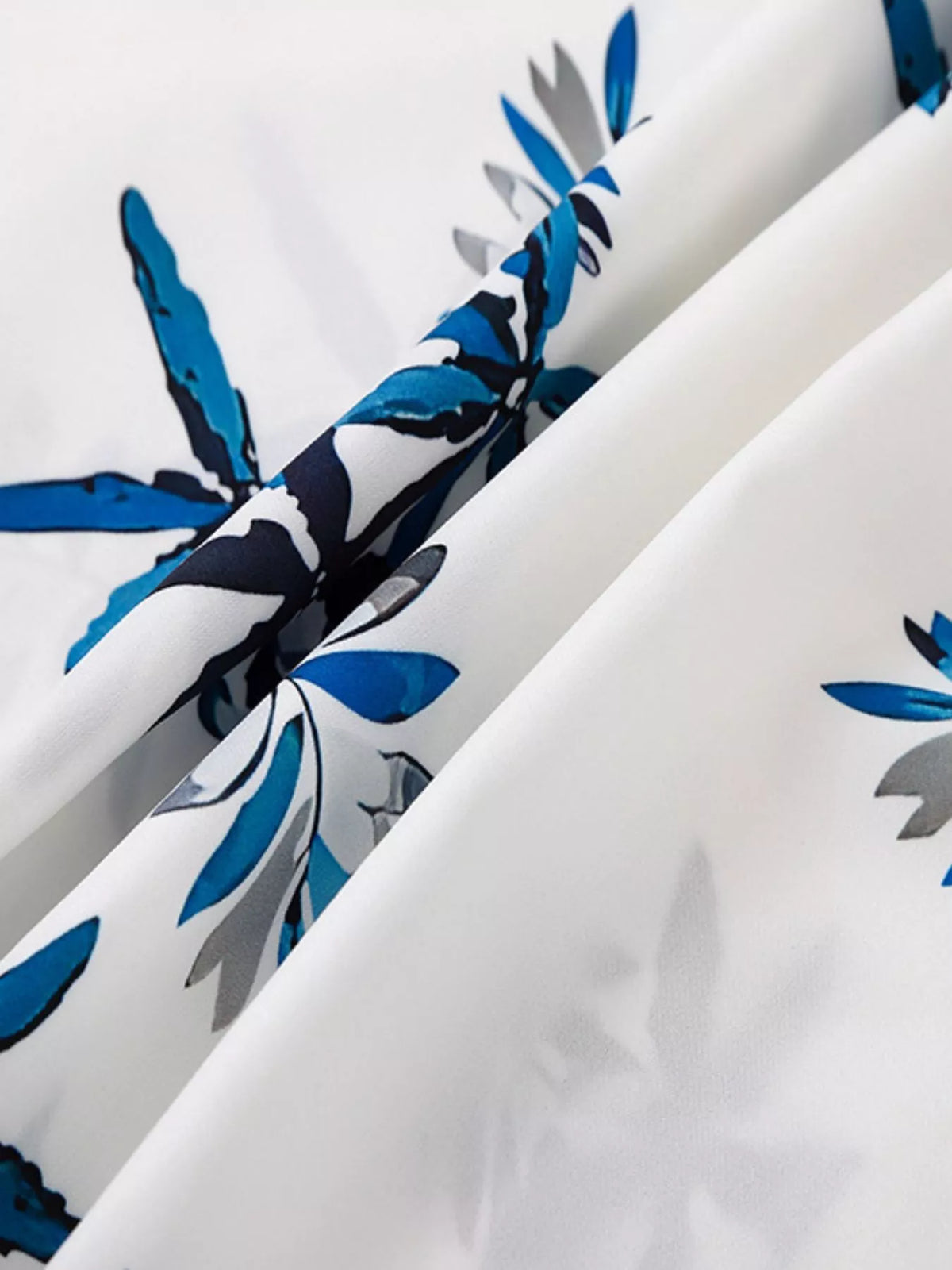 Close-up of blue tropical leaves printed on white fabric