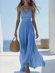 Model wearing a flowing sky-blue V-neck pleated maxi dress at the beach