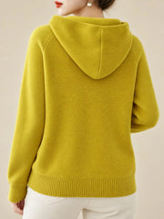Back view of the mustard-yellow sweater showing its hood and ribbed hem.