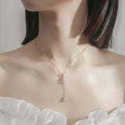 Close-up of rose-gold Y necklace against a white blouse