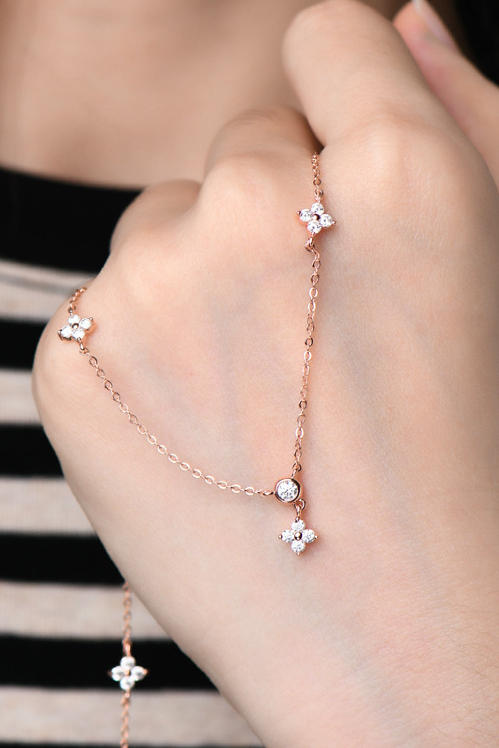 Close-up of small stones along silver-tone necklace chain on a hand