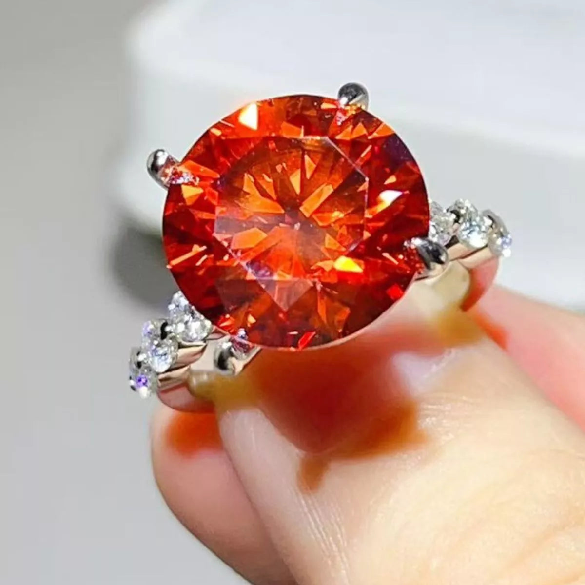 Orange-red centre-stone moissanite ring worn on hand