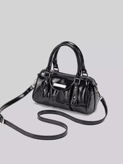Angled view of the black mini Boston bag with its long strap laid out beside it.