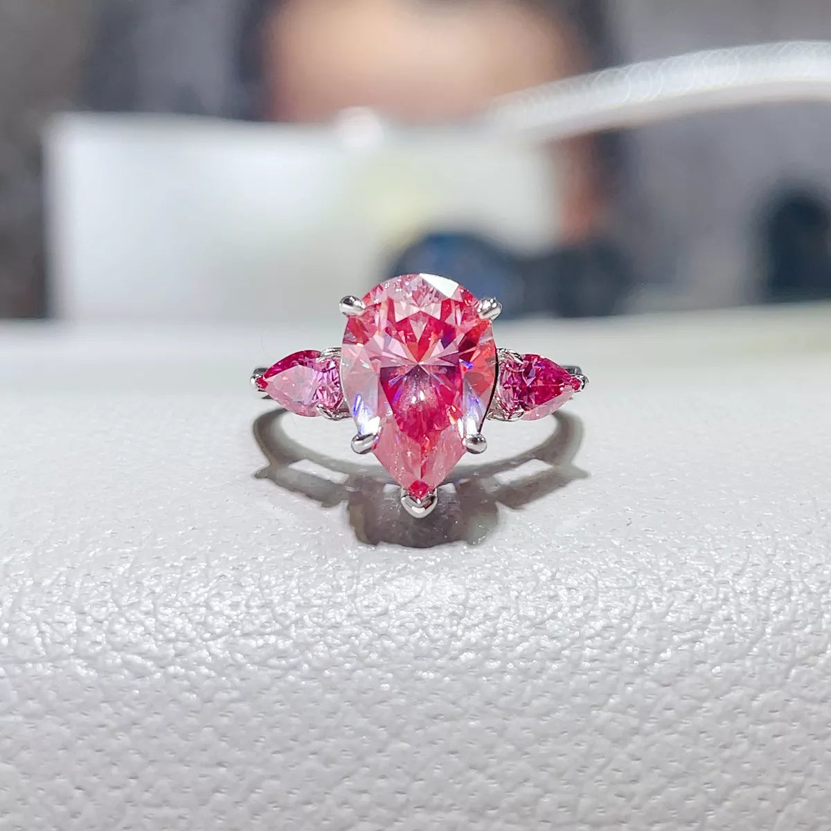 Front view of pink teardrop moissanite ring with matching side stones