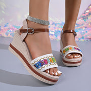 Side view of beige wedge sandals with embroidered straps and brown sole trim