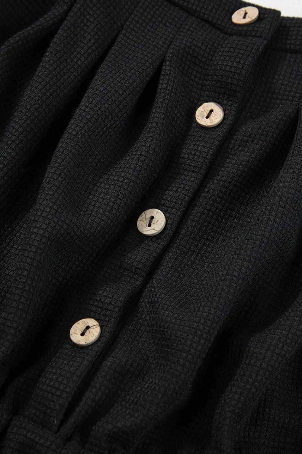 Black jumpsuit button placket with four light buttons