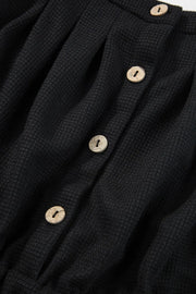 Black jumpsuit button placket with four light buttons