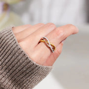 Crisscross two-tone ring worn on a hand in a taupe knit sleeve