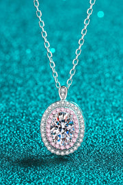 Oval clear-stone pendant with pink border displayed on teal