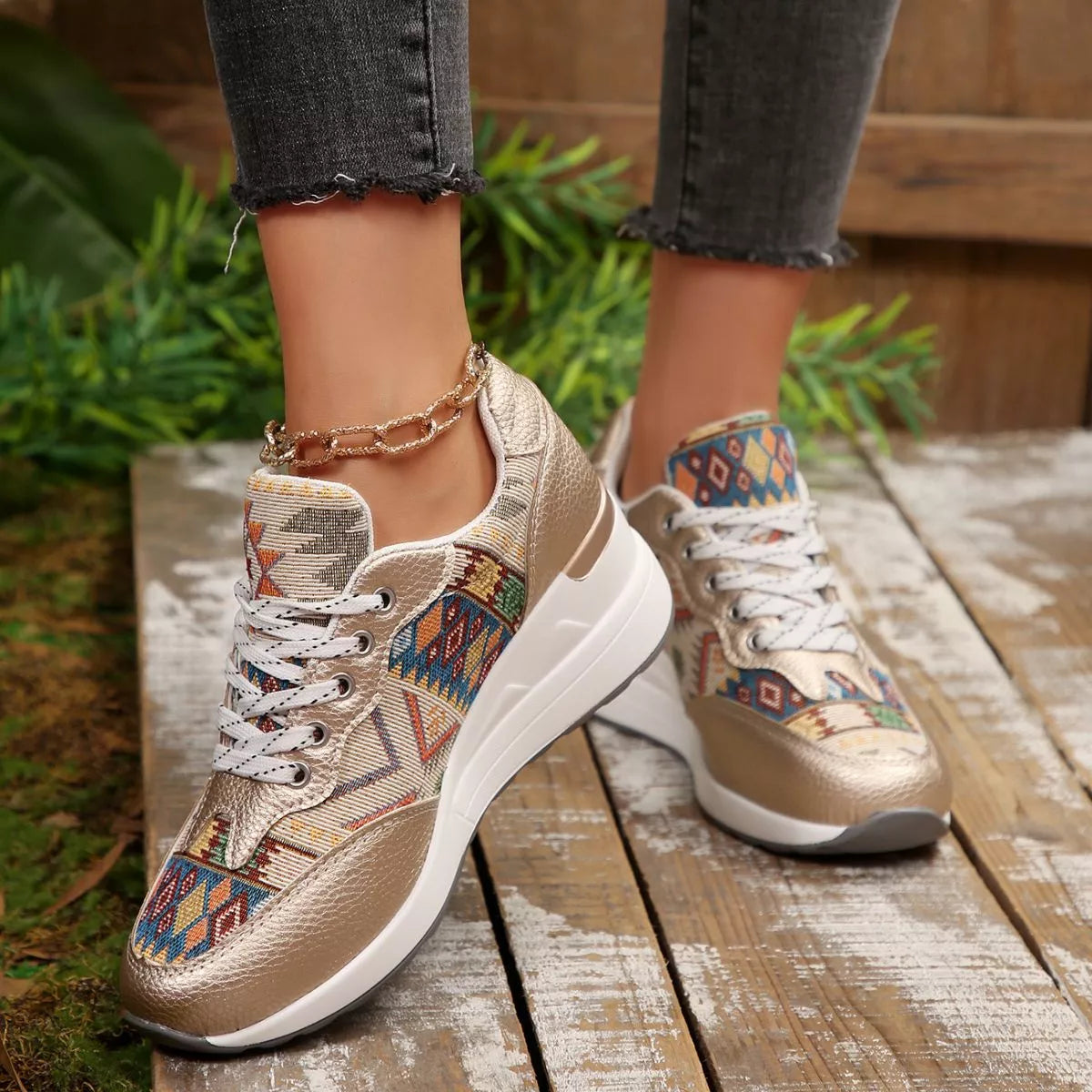 Pair of patterned lace-up wedge sneakers worn outdoors on a wooden walkway
