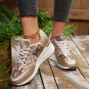 Pair of patterned lace-up wedge sneakers worn outdoors on a wooden walkway
