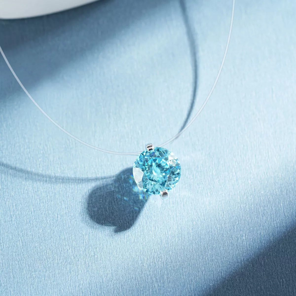 Close view of a pastel-blue round zircon pendant on a fine silver-tone chain