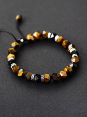 Brown faceted stone bracelet with black and silver-patterned spacer beads on a dark surface