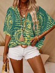 Green and yellow medallion-print blouse worn with white shorts and a woven handbag.