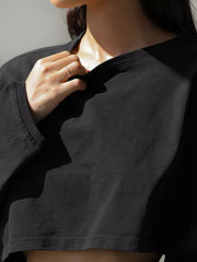 Close-up view of the neckline and front of a black cropped sweatshirt.