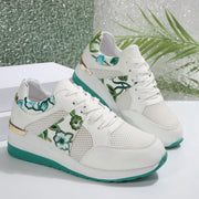 Pair of white sneakers with green floral panels and turquoise soles, side view