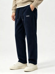Angled standing view of navy drawstring wide-leg pants with cream sneakers