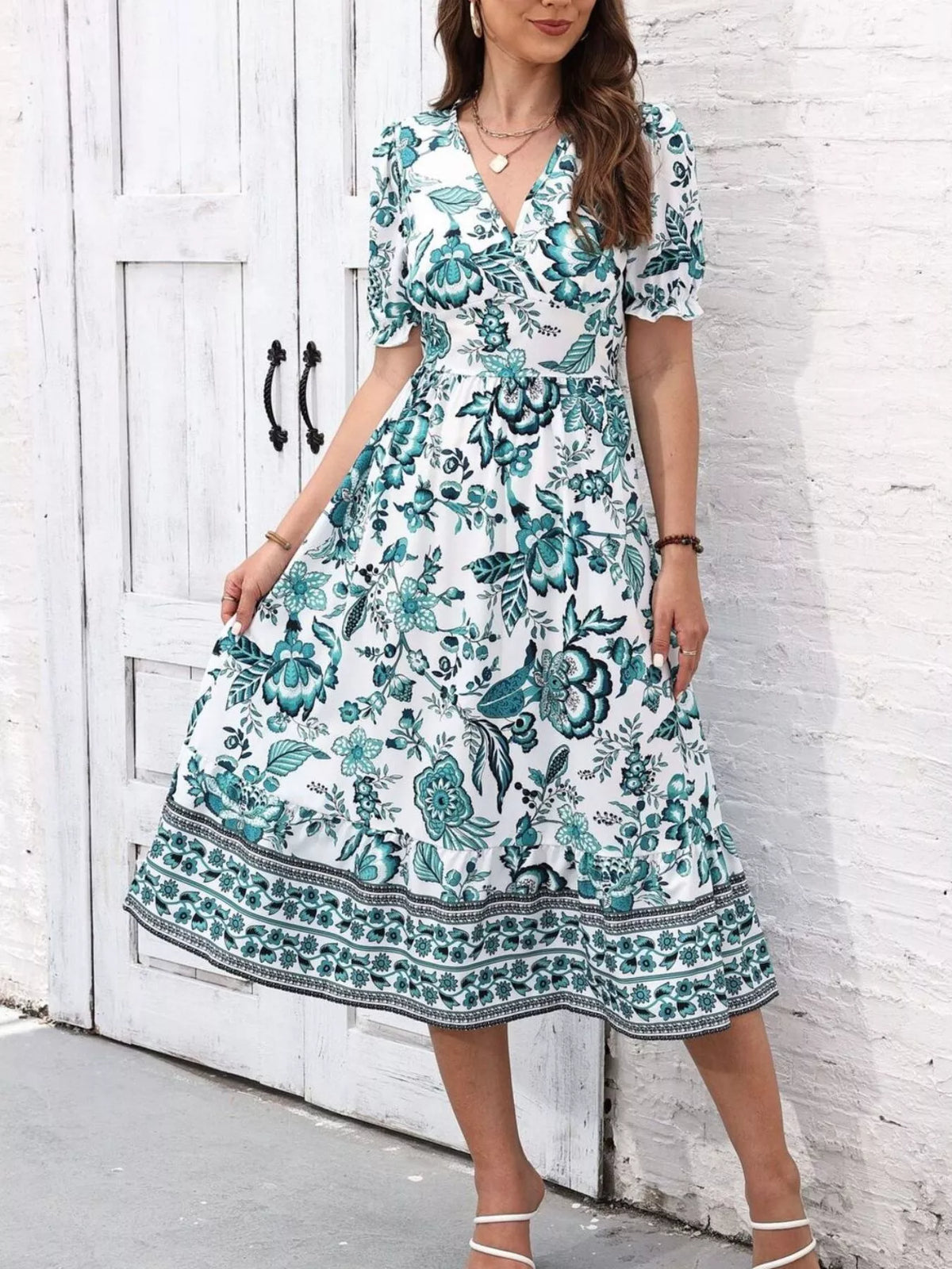 Green and white floral V-neck midi dress shown holding out one side of the flared skirt.