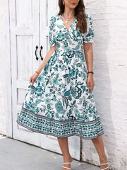 Green and white floral V-neck midi dress shown holding out one side of the flared skirt.