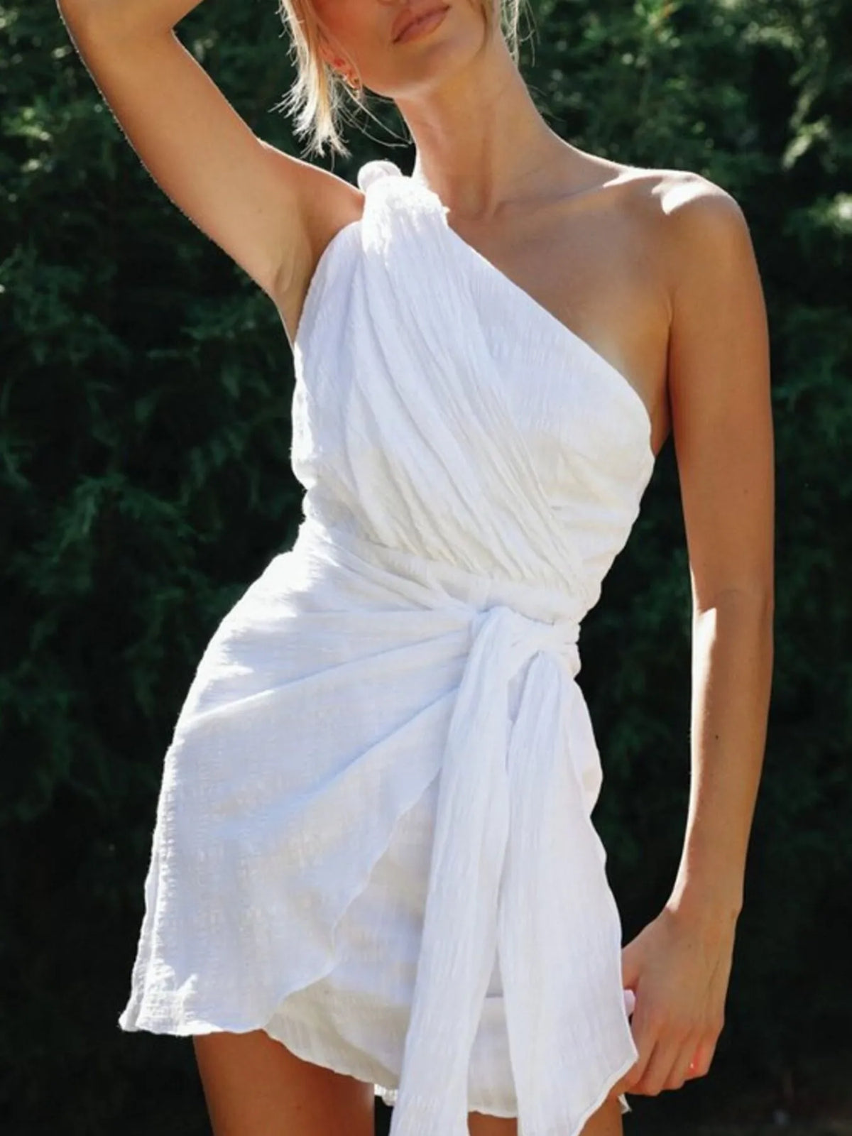 Angled view of white dress showing asymmetric neckline and draped front