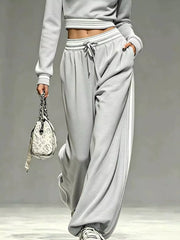Close detail of light gray half-zip cropped sweatshirt and matching pants with striped cuffs and drawstring waist