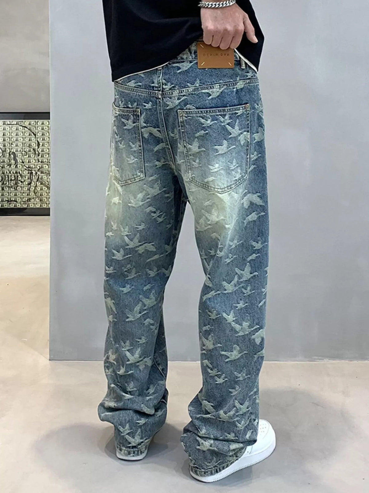 Back view of blue bird-print jeans showing two patch pockets and a waistband patch