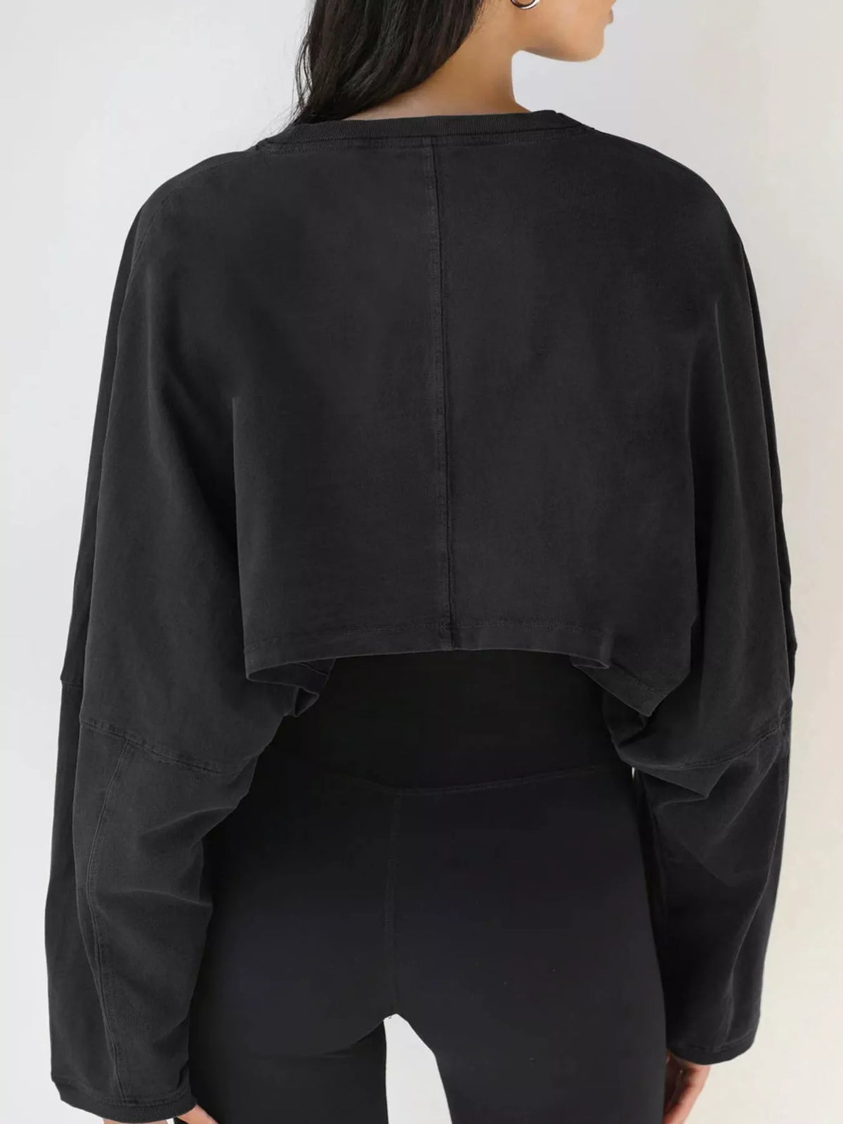 Back view of a black cropped sweatshirt with long sleeves.